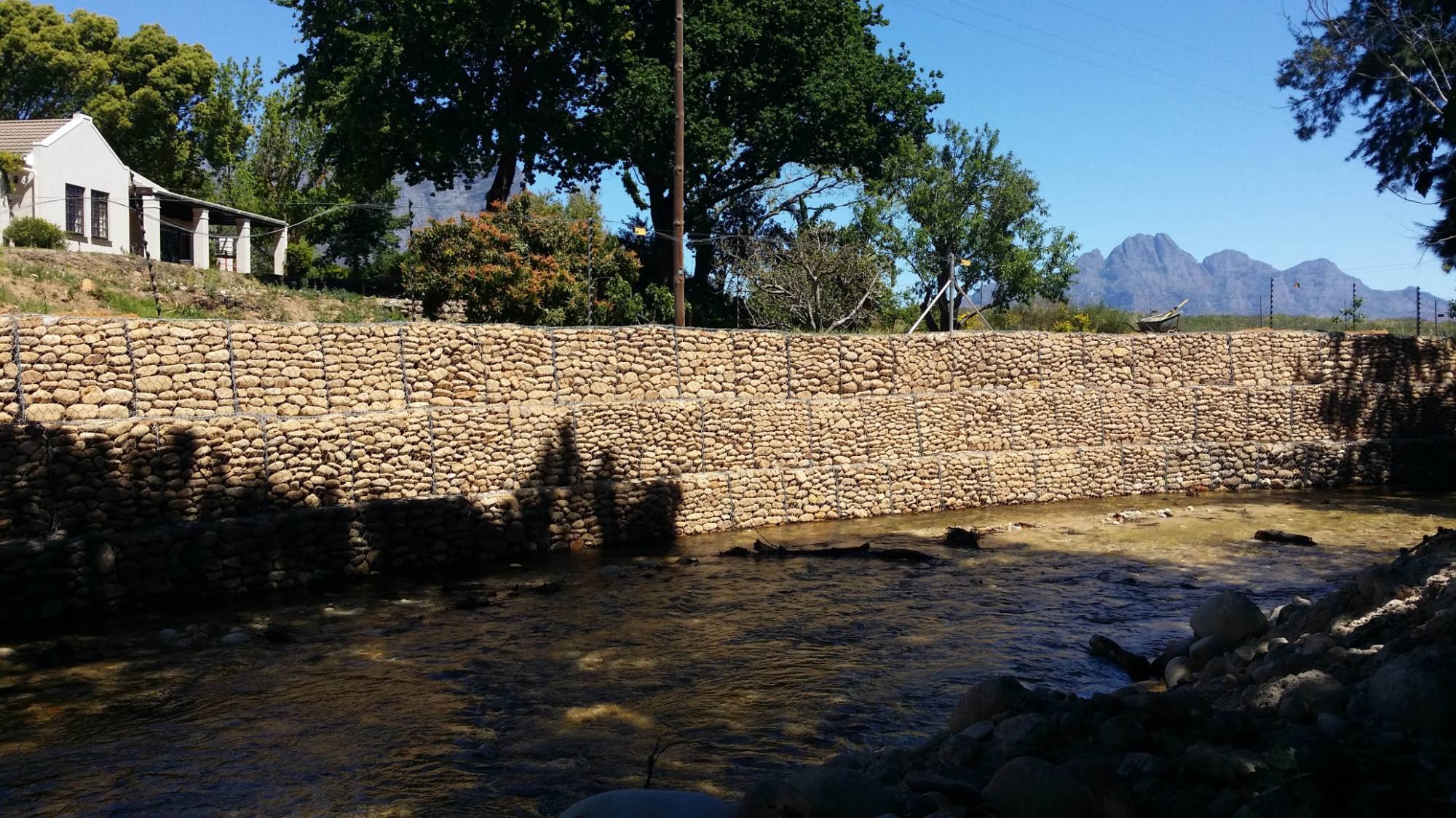 Stepped gabion wall lining a river bank with mountains behind