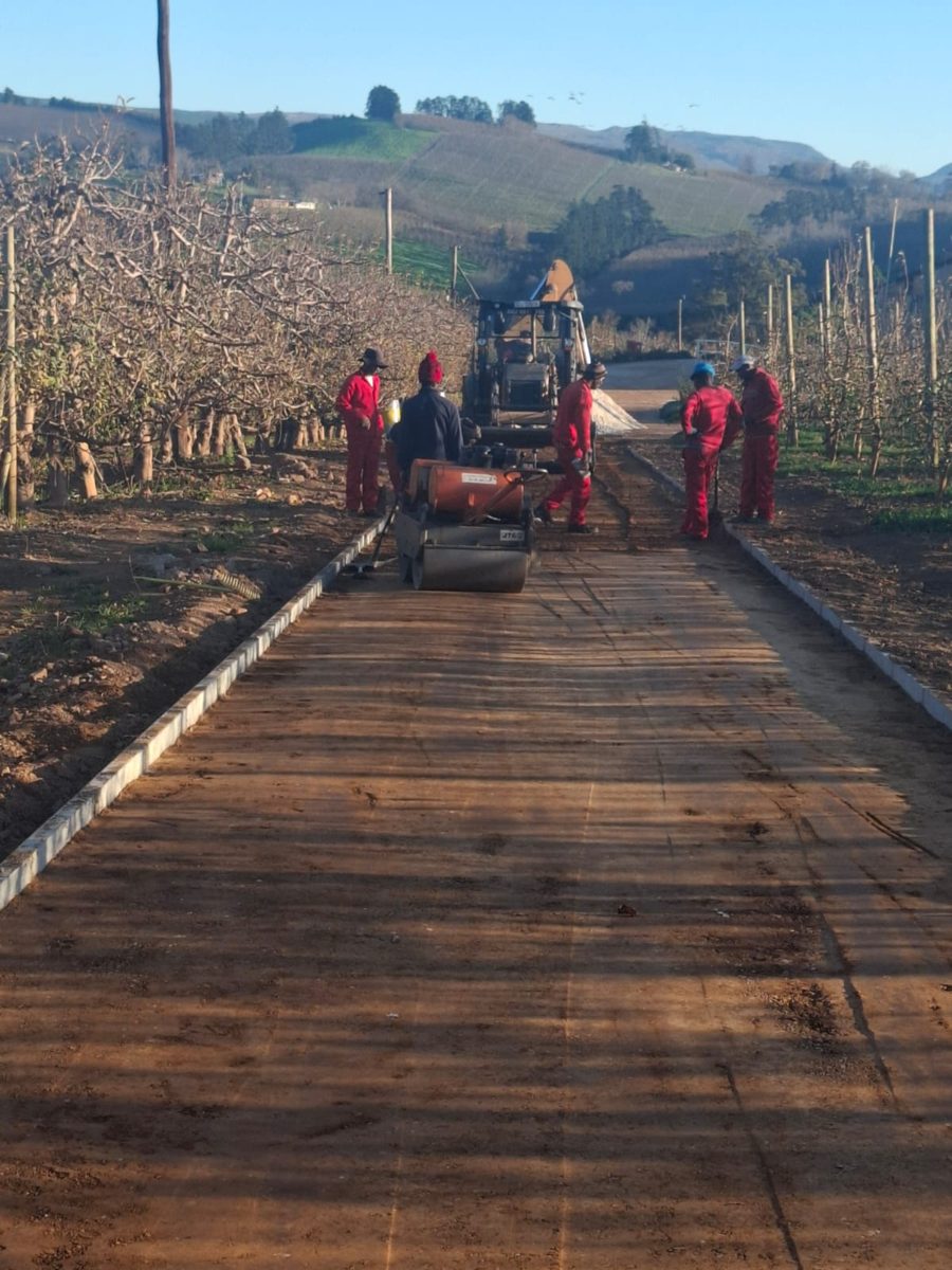 Crew compacting a kerbed access road base with a roller